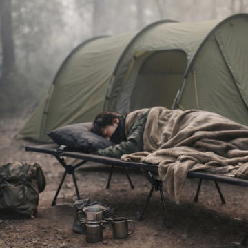 露營者在森林營地使用行軍床睡覺，呈現離地睡眠與真實露營情境